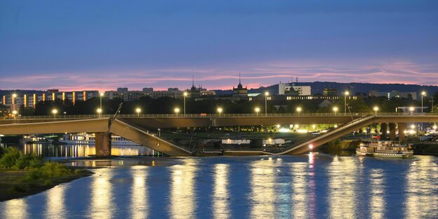 Die Carolabrücke in Dresden mit der eingestürzten Fahrbahn, erleuchtet im Abendlicht