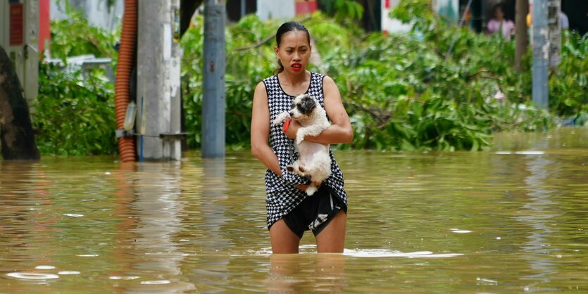 Eine Vietnamesin trägt am Donnerstag ihren Hund in einer überfluteten Straße in Hanoi.