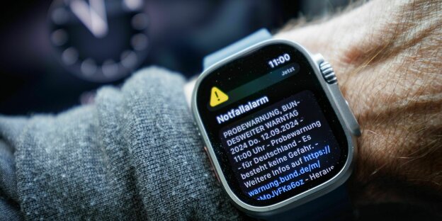 Eine Smartwatch am Handgelenk, auf dem Bildschirma erscheint der Notfallalarm