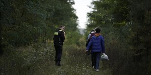 Ein Polizist neben Geflüchteten an der Grenze zu Polen.