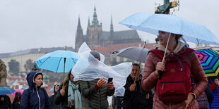 Menschen mit Regenschirmen auf der Karlsbrücke in Prag