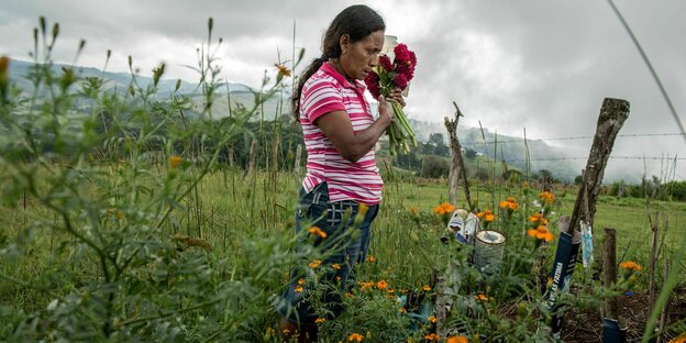 Eine Frau legt Blumen an einer Beerdigungsstätte nieder.