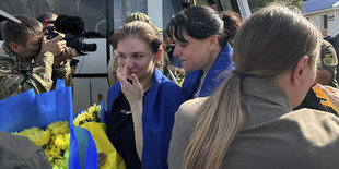 Frau mit Ukraineflagge vor einem Bus