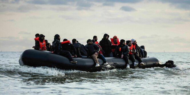 Migranten sitzen auf einem Schlauchboot und versuchen, den Ärmelkanal zu überqueren.