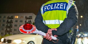 Rückenansicht eines Polizisten mit Kelle in der Hand