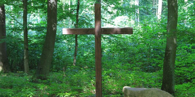 Ein Holzkreuz in einem Wald.