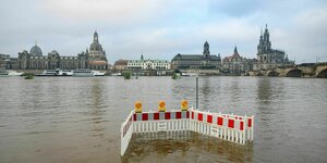 Absperrungen stehen im Wasser vor der Altstadtkulisse Dresdens