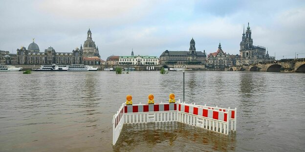 A wall is erected over the water with Dresden's old town in the background.