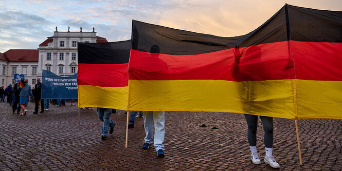 Menschen verstecken sich hinter einer großen deutschlandfahne