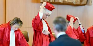 Christine Langenfeld (l-r), Vorsitzende Doris König und Astrid Wallrabenstein - setzen sich nach der Urteilsverkündung im Verhandlungssaal des Bundesverfassungsgerichts die roten Hüte ab