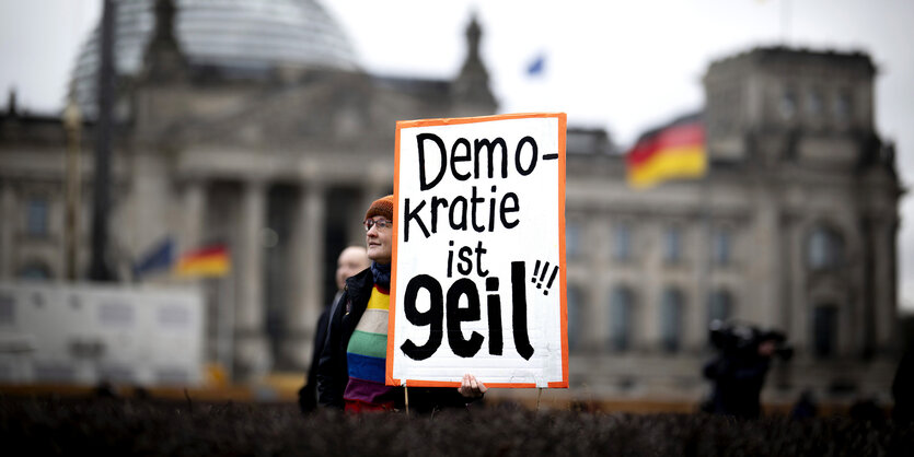 Protestierende hält ein Schild mit der Aufschrift: "Demokratie Ist Geil", während einer Kundgebung vor dem Reichstag in Berlin.