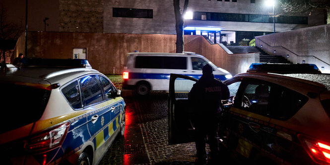 Polizeifahrzeuge stehen in dunkler Nacht vor einem Gebäude