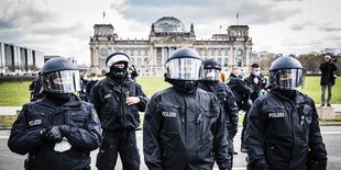 Polizisten in Uniform und mit Schutzhelmen stehen vor dem Reichstag in Berlin