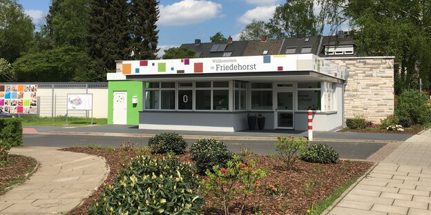 Ein Empfangsgebäude an einer Einfahrt. Auf dem Gebäude steht: "Willkommen in Friedehorst"