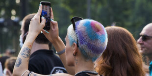 Frau mit buntgefärbten Haaren und Mobiltelefon