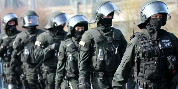 Polizist*innen in voller Kampfausrüstung mit Helm und Schienbeinschutz