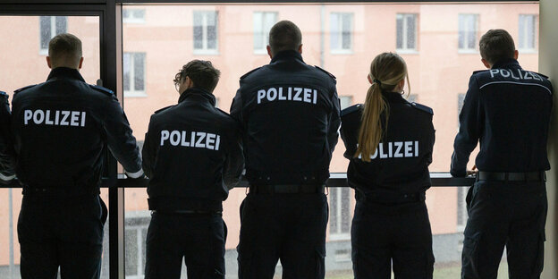 Polizisten stehen vor einem Fenster