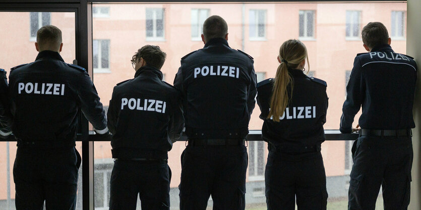 Polizisten stehen vor einem Fenster