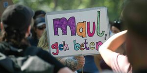 Ein Protestschild, auf dem steht: "Maul, geh beten"