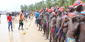 Teilnehmer des Schwimmwettbewerbs im Senegal stehen direkt am Wasser vor dem Start.