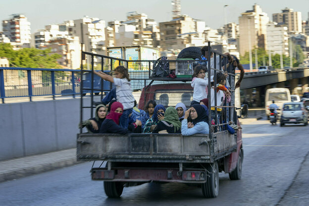 Frauen und Kinder sitzen auf einem Pickup, der auf einer Straße in Beirut fährt