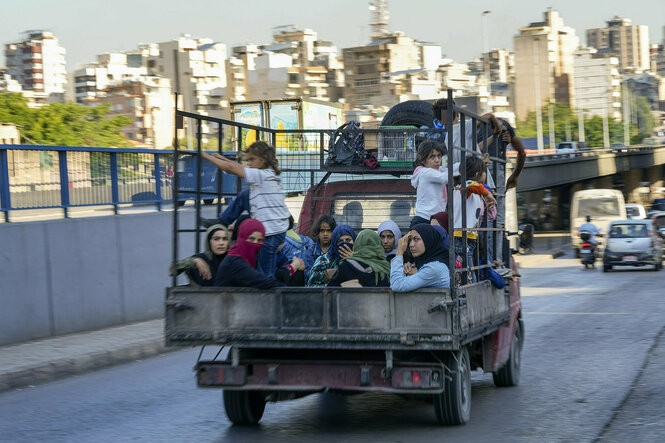 Frauen und Kinder sitzen auf einem Pickup, der auf einer Straße in Beirut fährt