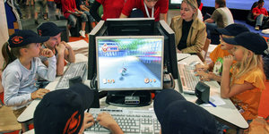 Eine Gruppe Kinder starrt gebannt auf Bildschirme und spielt Computerspiele.