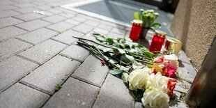 Blumen und Kerzen liegen nach einem tödlichen Messerangriff vor einem Hauseingang in Berlin-Friedrichsfelde.