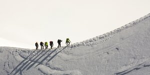 Sechs Menschen besteigen einen schneebedeckten Berg