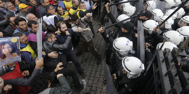 Demonstranten und Polizisten mit Schlagstöcken stehen sich gegenüber