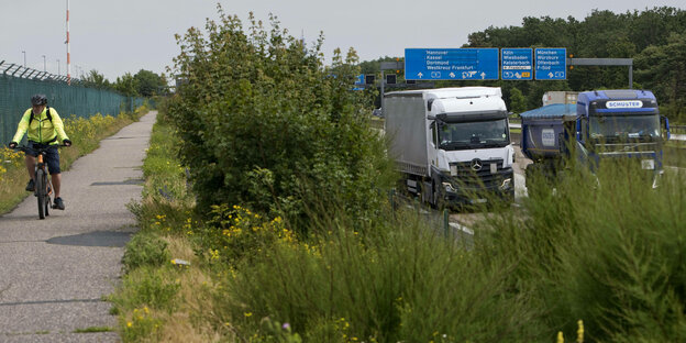 Ein Fahrradfahrer fahrt auf einem Fahrradweg neben dem Verkehr auf der Autobahn A5.