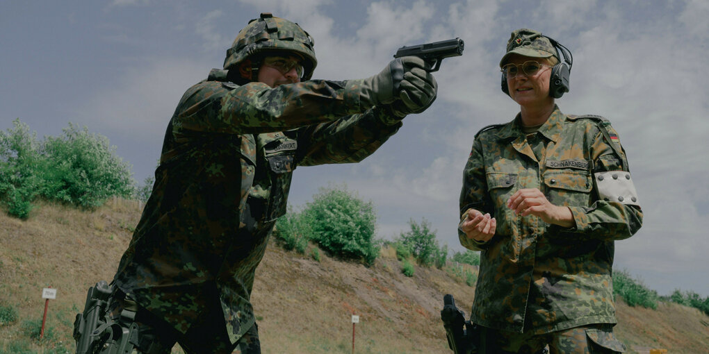 Ein Soldat der Bundeswehr richtet seine Pistole auf ein Ziel, eine Bundeswehr-Soldatin sieht dabei zu.