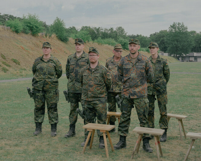 Uniformierte Bundeswehrsoldaten stehen auf einer Wiese.