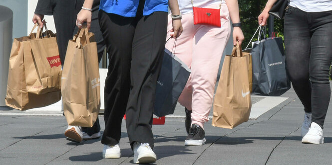 Eine Gruppe Frauen bepackt mit Einkaufstueten in in der Outlet-City in in Metzingen.