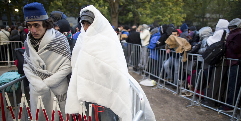 Flüchtlinge warten in Decken gehüllt vor dem Lageso