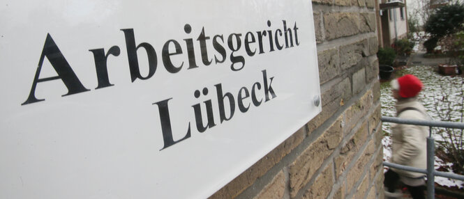 Schild mit der Aufschrift "Arbeitsgericht Lübeck" an einer Ziegelwand