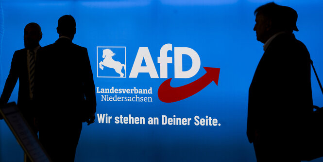 Schattenrisse von Menschen , die vor einem AfD-Plakt stehen. Drauf ist zu lesen: "Wirstehen an deiner Seite - AfD Landesverband Niederachsen"