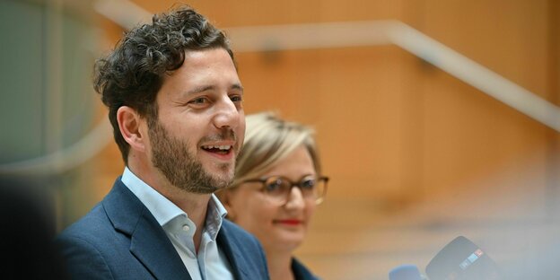 Zu sehen sind Felix Banaszak und Franziska Brantner vor einer Holzwand. Die beiden kandidieren für den Grünen-Parteivorsitz.