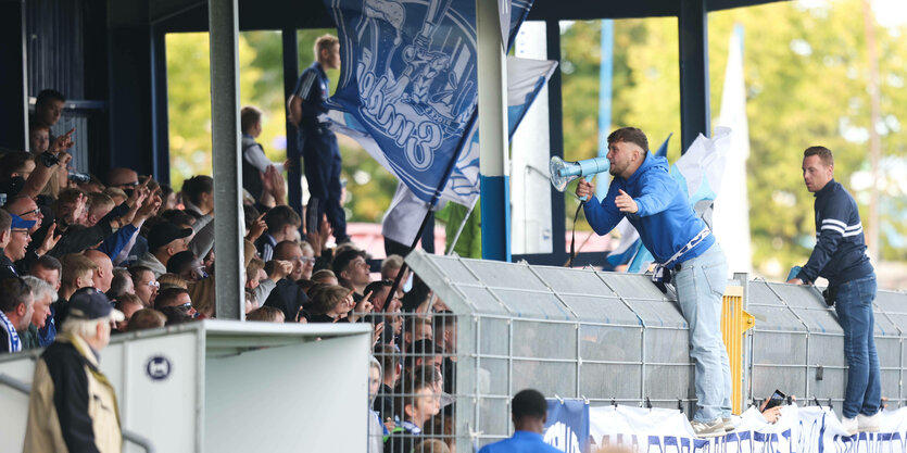 Ein Mann mit Megafon feuert Fans der Kickers Emden an