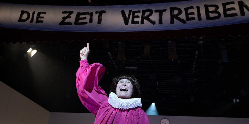 Eine Person in purpurner Robe mit Halskrause reckt den Zeigefinger. Über ihr auf einem Banner steht: „Die Zeit vertreiben“