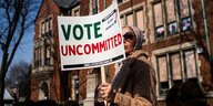 Eine Frau hält ein Schild Vote Uncommitted, heißt ungültige Stimmagabe