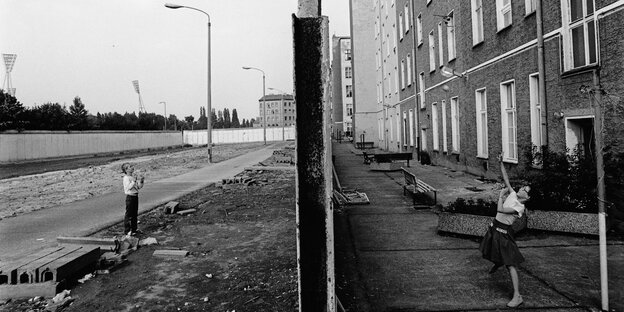 Auf dem Foto wirft ein Mädchen ihrem Spielgefährten, der in dem ehemaligen Todesstreifen steht, einen Ball über die Mauer an der Bernauer Straße zu. (Foto: 19.06.1990)