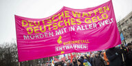 Demonstrierende mit einem großen Banner der Gruppe Rheinmetall Entwaffnen, auf dem steht: „Deutsche Waffen, deutsches Geld, morden mit in aller Welt“ auf einer Demo am 25. 11. 2023 in Berlin