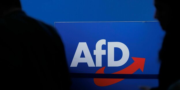 Delegierte gehen vor dem Parteilogo bei dem AfD-Bundesparteitag in Magdeburg