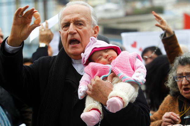 Ein Mann hält ein Baby im Arm und einen Plastikfötus in der Hand