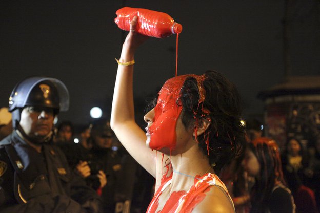 Eine Frau gießt sich rote Farbe über den Kopf
