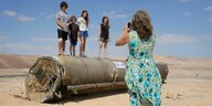 Eine Person fotografiert vier weitere Menschen, die auf den Überresten einer iranischen Rakete stehen