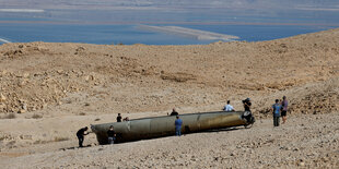 Menschen stehen um die offensichtlichen Überreste einer ballistischen Rakete, die nach einem Angriff des Irans auf Israel in der Wüste liegt, in der Nähe der südlichen Stadt Arad, Israel 2. Oktober 2024