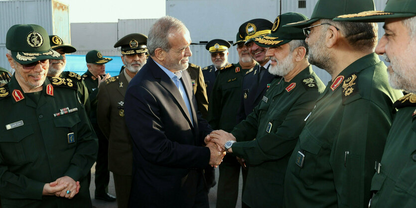 Der iranische Präsident Masoud Pezeshkian (M,l) schüttelt dem Kommandeur der Luft- und Raumfahrttruppen des Korps der Islamischen Revolutionsgarden die Hand