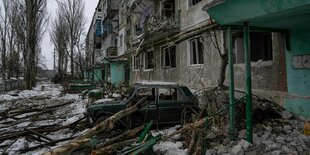 Ein zerstörtes Auto steht vor einem Wohnhaus in Wuhledar, das von den russischen Streitkräften schwer bombardiert wurde